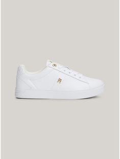 Tommy Hilfiger women's sneaker. Dial up your sporty luxe style in these leather sneakers, detailed with branded gold-tone eyelets and a polished TH monogram plaque.  Material: 100% Leather (fwa). Leather Low-top Sneakers With Foil Embossed Logo, Low-top Leather Sneakers With Foil Embossed Logo, White Leather Sneakers With Foil Embossed Logo, Gold Luxury Sneakers With Metallic Logo, Luxury Gold Sneakers With Metallic Logo, Classic Tommy Hilfiger Leather Sneakers, Elegant Low-top Sneakers With Perforated Toe Box, Tommy Hilfiger Sneakers Women, Tommy Hilfiger Sneakers