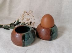 two brown and green vases sitting next to each other on a white table cloth