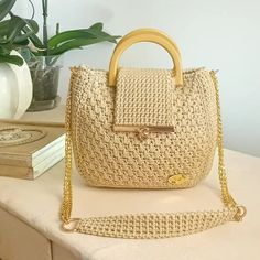 a white purse sitting on top of a table next to a book and potted plant