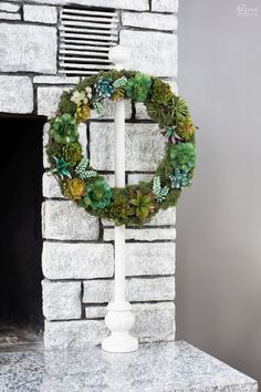 a wreath with succulents is placed on top of a stone fireplace