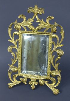 an ornate gold framed mirror on a gray background with the reflection in it's center