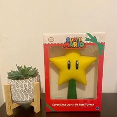 a yellow star light - up toy sitting on top of a table next to a potted plant