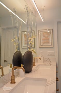 two vases with flowers are sitting on the bathroom counter