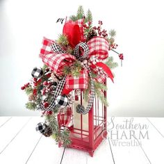 a red and white christmas lantern with a bow on it's front, sitting on a wooden table