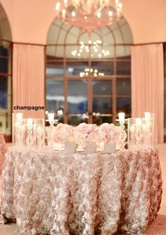 a table with candles and flowers on it in front of a large chandelier