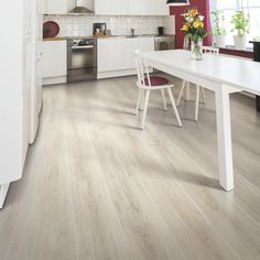 a white table and chairs in a room with red walls, hardwood flooring and cabinets