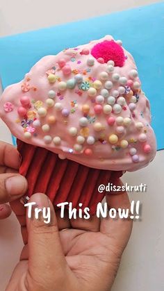 a hand holding a pink cupcake with sprinkles on it and the words try this now