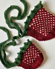 two crocheted strawberries with green stems and white dots on them, sitting next to each other