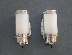 two wall sconces with white glass and silver trimmings on the sides