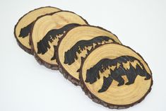 four wooden coasters with black bear designs on each one and brown wood slices in the middle