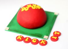 a red ball sitting on top of a green mat next to some buttons and letters