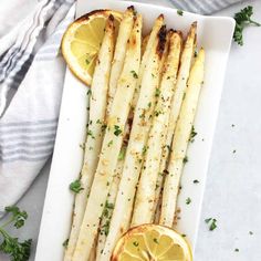 grilled asparagus with lemon and parsley on a white serving platter