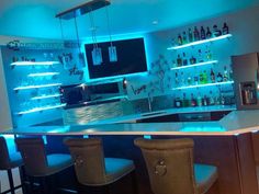 a bar with several bottles on the shelves and blue lights in the back ground, along with four stools