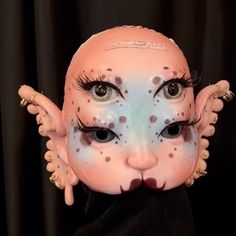 a close up of a doll with makeup on it's face and wings around the eyes