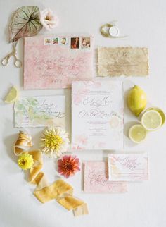 the wedding stationery is laid out with lemons, flowers, and other items