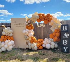 an orange and white balloon arch for a baby shower