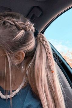 a woman sitting in the back seat of a car with her hair in a pony tail braid