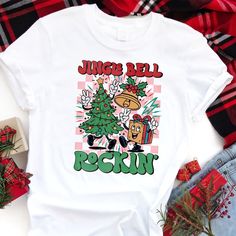 Get into the holiday groove with this fun and festive "Jingle Bell Rockin'" tee! Featuring a retro-inspired design with a dancing Christmas tree, a cheerful gift box, and a jingle bell, this shirt captures the playful energy of the season. The vibrant colors and playful characters will bring a smile to anyone's face. It's the perfect tee for holiday parties, family gatherings, or simply spreading Christmas cheer wherever you go. So put on your dancing shoes and get ready to rock around the Chris Holiday Tees, Spreading Christmas Cheer, Dancing Shoes, Christmas Characters, Jingle Bell, Christmas Tees, Jingle Bells, Retro Christmas, Classic Christmas