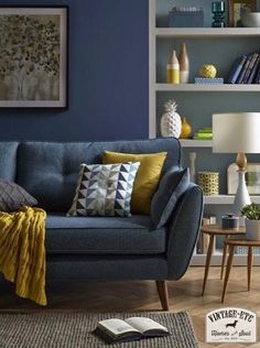 a living room with blue walls and yellow throw pillows on the couch in front of it