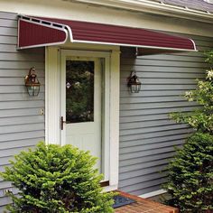 the front door of a gray house with white trim and an awning over it