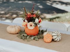 an arrangement of flowers and pumpkins on a table