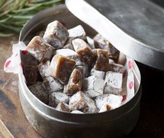 a metal container filled with sugar cubes on top of a wooden table