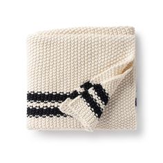 a knitted blanket with black and white stripes on the edges, folded up to reveal a bow