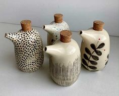 three ceramic vases with cork tops are lined up