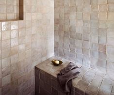 a bath room with tiled walls and a gold bowl on the ledge next to it