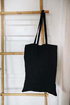 a black tote bag hanging on a wooden ladder