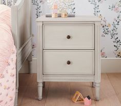 a white wooden dresser sitting next to a child's bed