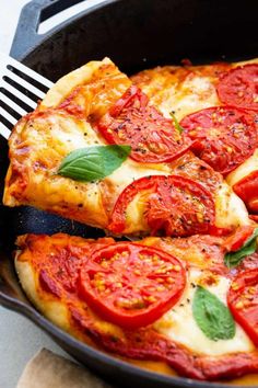 a close up of a pizza in a pan on a table with a fork next to it