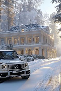 a white car driving down a snow covered road in front of a large house with lights on