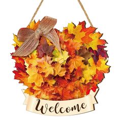 a welcome sign hanging from a rope with autumn leaves around it and a bow on top