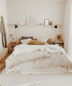 an unmade bed with white sheets and pillows in a bedroom next to a window