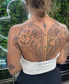 the back of a woman's body with tattoos on her upper and lower half