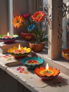 brightly colored paper flowers sit in front of a window sill with lit candles on the windowsill