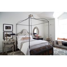 a bedroom with a four poster bed and white walls