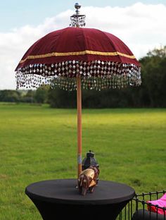 an umbrella that has been decorated with beads and chains on it in the grass near some trees