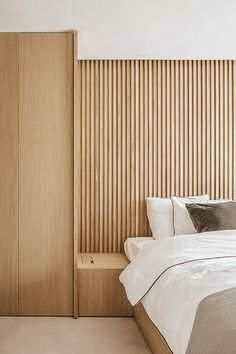 a bed sitting next to a wooden wall in a bedroom