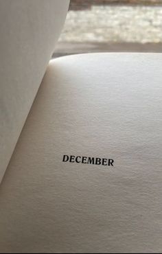 an open book with the word december written on it's side, in front of a window