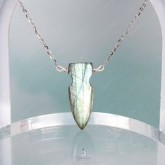 This one-of-a-kind arrow Labradorite necklace boasts a stunning arrow-shaped pendant on a sturdy 925 sterling silver chain. The wire used is also made of high-quality 925 sterling silver. The arrow-shaped Labradorite stone showcases a mesmerizing green hue with a dazzling blue flash when hit by sunlight. Make a statement by adding this handcrafted Labradorite necklace to your fine jewelry collection or give it as a gift to a special someone. Materials: Labradorite, 925 sterling silverPendant dim Handmade Silver Labradorite Crystal Necklaces, Elegant Silver Labradorite Necklaces, Elegant Silver Labradorite Necklace, Unique Silver Labradorite Necklace, Handmade Sterling Silver Arrowhead Necklace, Silver Labradorite Necklace, Nature-inspired, Stone Pendant Necklace, Labradorite Necklaces, Labradorite Stone