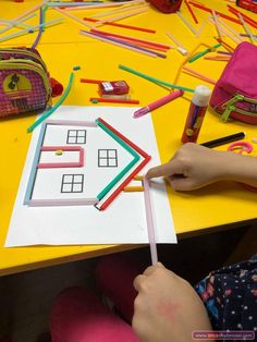 a child is making a house out of construction paper with crayons on the table