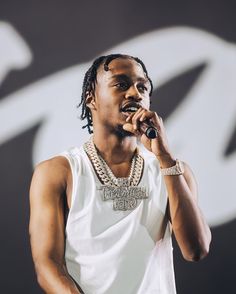 a man with dreadlocks holding a microphone up to his mouth and wearing a white tank top