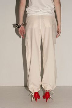 Loosely tailored cargo pant in a soft yet structured cotton. Straight leg with tie at ankle, cinch for a more tapered silhouette. Side pockets and oversized patch pockets above knee. Made in New York City. Fabric is 100% cotton. Avery is 5'10", bust 31", waist 24", hip 35", and is wearing a size S. Spring Straight Parachute Pants With Cargo Pockets, High-waisted Cotton Cargo Pants With Multiple Pockets, Wide-leg Parachute Pants With Side Pockets For Work, Relaxed Fit Cargo Style Parachute Pants, Relaxed Fit Ankle-length Cargo Parachute Pants, Relaxed Fit Cargo Parachute Pants Ankle-length, High-waisted Parachute Pants With Cargo Pockets For Workwear, Straight Parachute Pants With Cargo Pockets For Workwear, Spring High-waisted Cargo Pants With Pockets