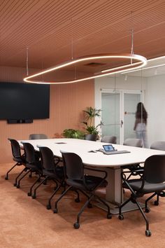 an office meeting room with a long table and chairs in front of a flat screen tv