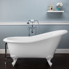 an old fashioned claw foot bathtub in a bathroom with blue walls and wood floors