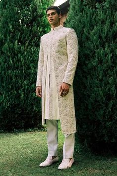 Ivory herringbone embroidered sherwani with velvet dori wave work. Comes with ivory cotton silk kurta and slim trouser.
Component: 3
Pattern: Embroidery
Type Of Work: Dori work
Neckline: Band Collar
Sleeve Type: Full sleeves
Fabric: Sherwani: Herringbone, Kurta and Pant: Cotton Silk
Color: Ivory
Other Details: 
Note: The outfit worn by the model on the left is not for sale
Occasion: Wedding - Aza Fashions Herringbone Embroidery, Ivory Sherwani, Embroidered Sherwani, Dori Work, White Kurta, Silk Kurta, Slim Trousers, Groom Outfit, Pattern Embroidery