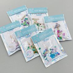 five bags of bead and charm kits on a gray surface with the package in it's packaging