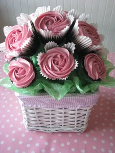 a basket filled with pink cupcakes sitting on top of a table